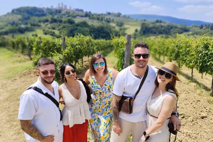 Visitors posing in a lush vineyard with scenic views on a Tuscany Wine Tour from Rome.