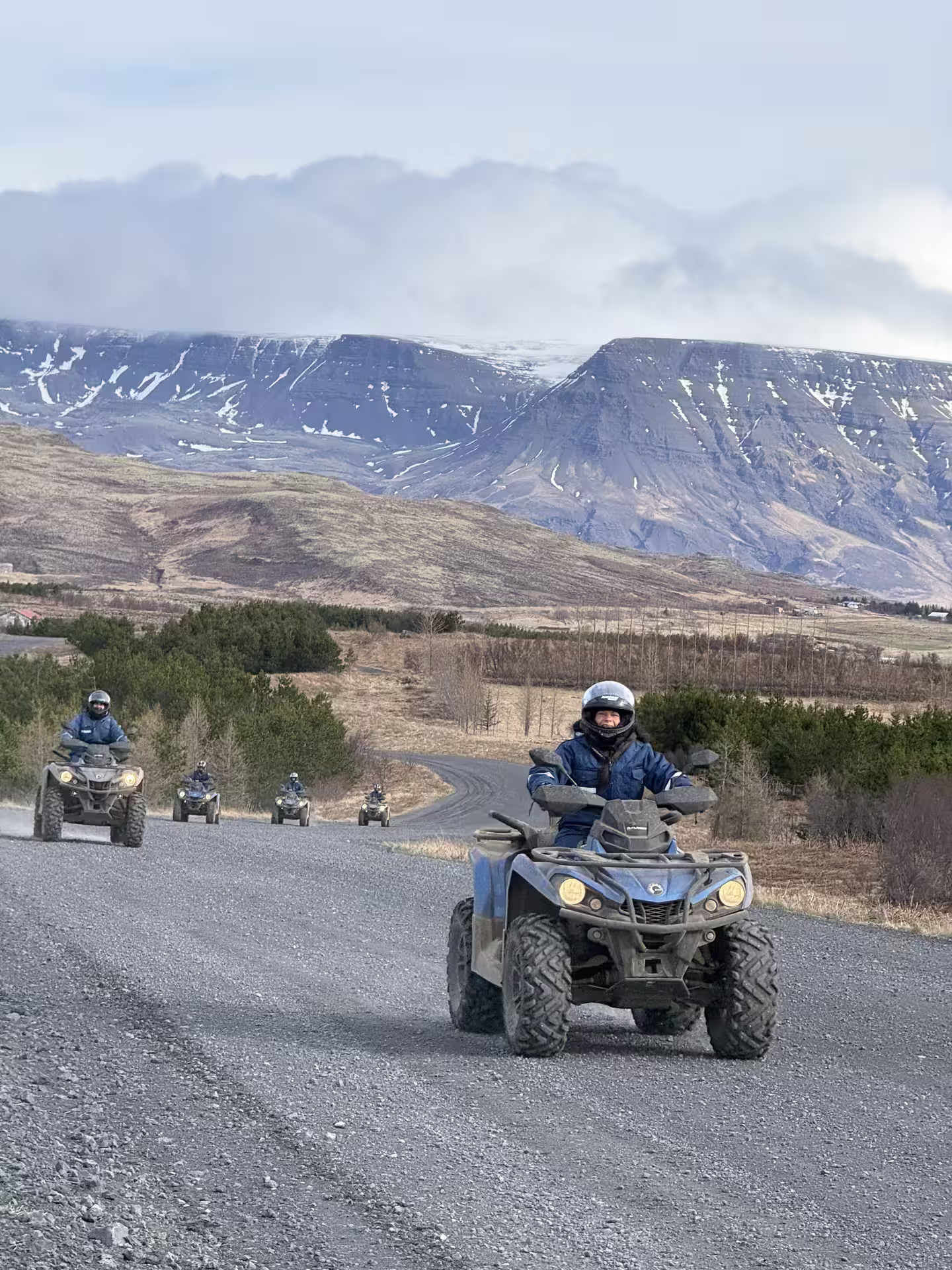 Riders on ATVs explore scenic gravel trails against a backdrop of snow-capped mountains during the Twin Peaks adventure tour.