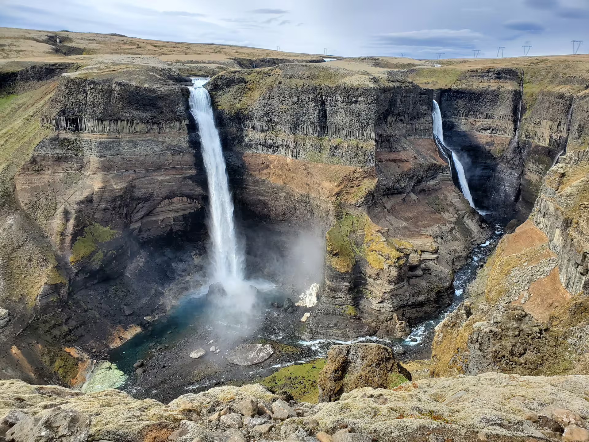 Dramatic twin waterfalls plunging into a deep basalt canyon on a private Super Jeep hidden waterfall Iceland tour