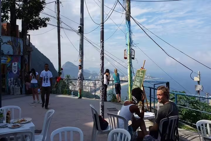 Tourists enjoy a meal with panoramic views of Vidigal Favela and the coast on the Hike Two Brothers Hill tour.