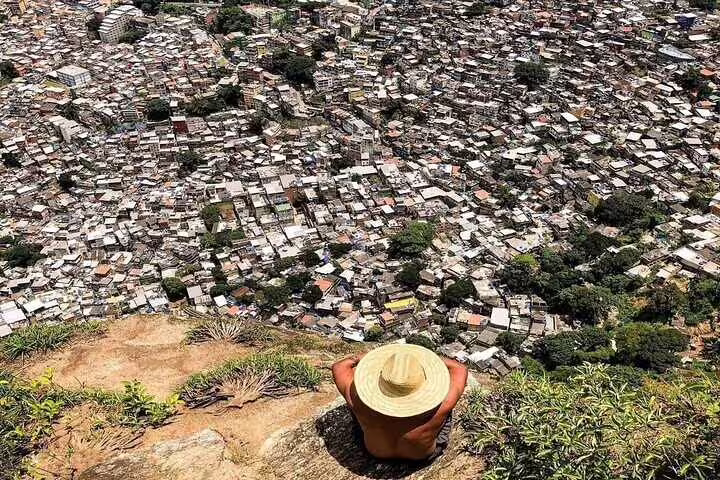 View from Two Brothers Hill overlooking Vidigal Favela, featuring a hiker with a hat enjoying the panoramic scenery.