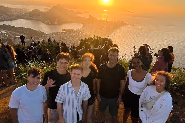 Visitors gather on Two Brothers Mountain for a breathtaking sunset view over Rio de Janeiro's coastline.