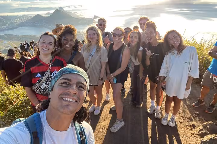 Group enjoying the stunning sunset view from Two Brothers hike in Rio de Janeiro, showcasing the beautiful coastline.
