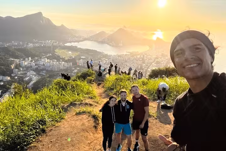 Hikers enjoy a breathtaking sunset view from Two Brothers peak overlooking Rio de Janeiro's coastline and cityscape.