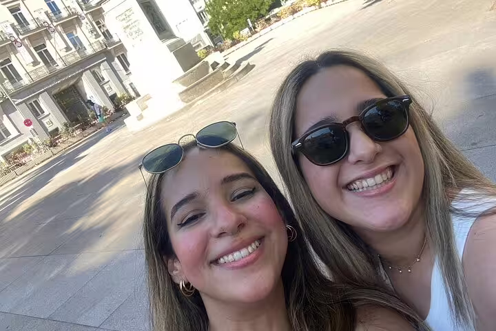 Two smiling women taking a selfie in a sunny Madrid plaza during a walking tour