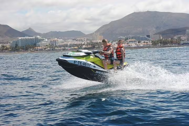 Two people enjoy a thrilling jet ski ride near scenic coastal mountains during a 2-hour safari adventure.