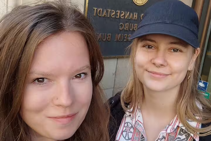 Two young women taking a selfie in front of a Hamburg city hall sign