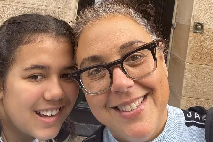 Two smiling women posing for a selfie in front of a historic stone building doorway