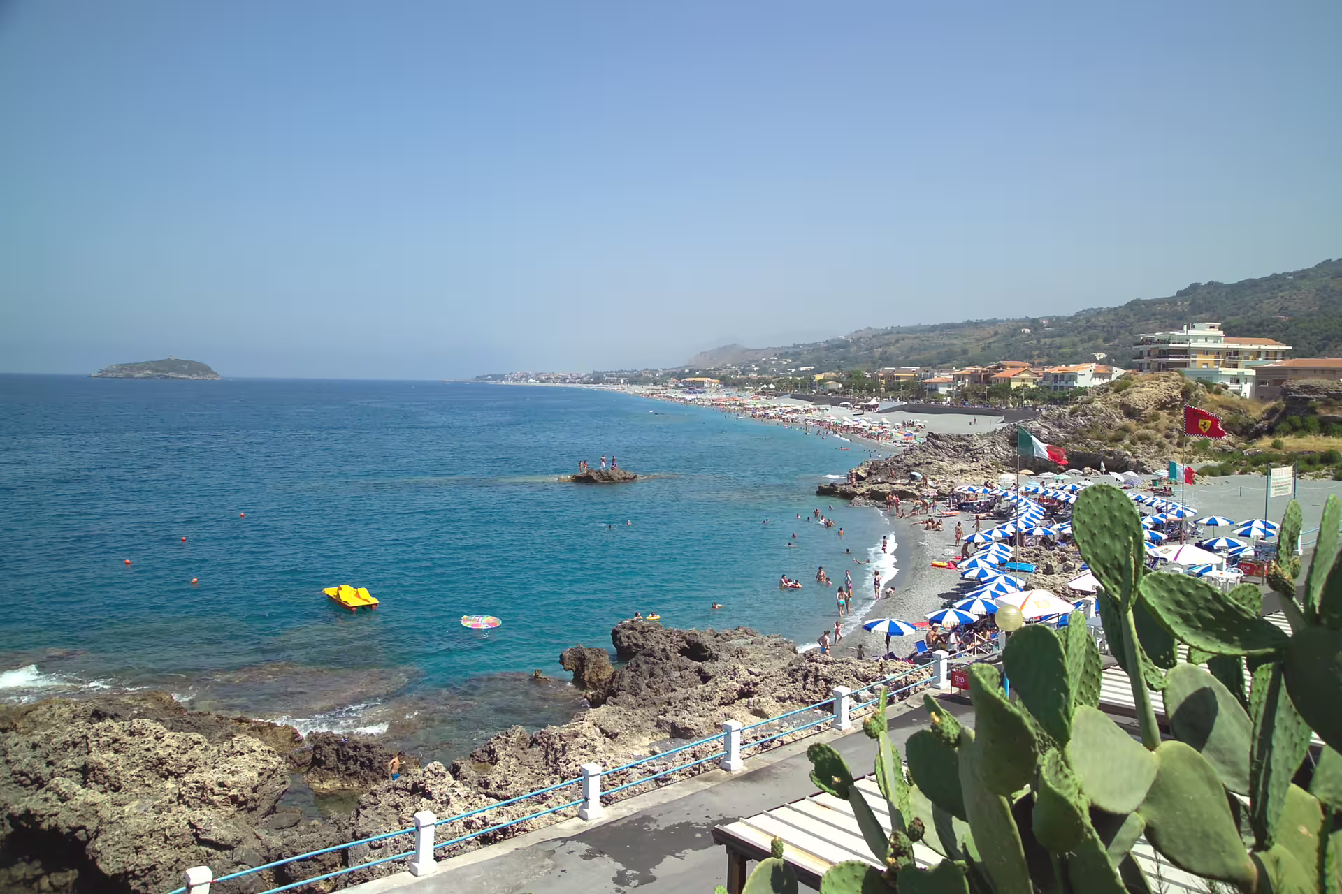 Sunny Tyrrhenian Sea beach near Diamante, Italy with turquoise water, umbrellas and rocky coast on Calabria holiday