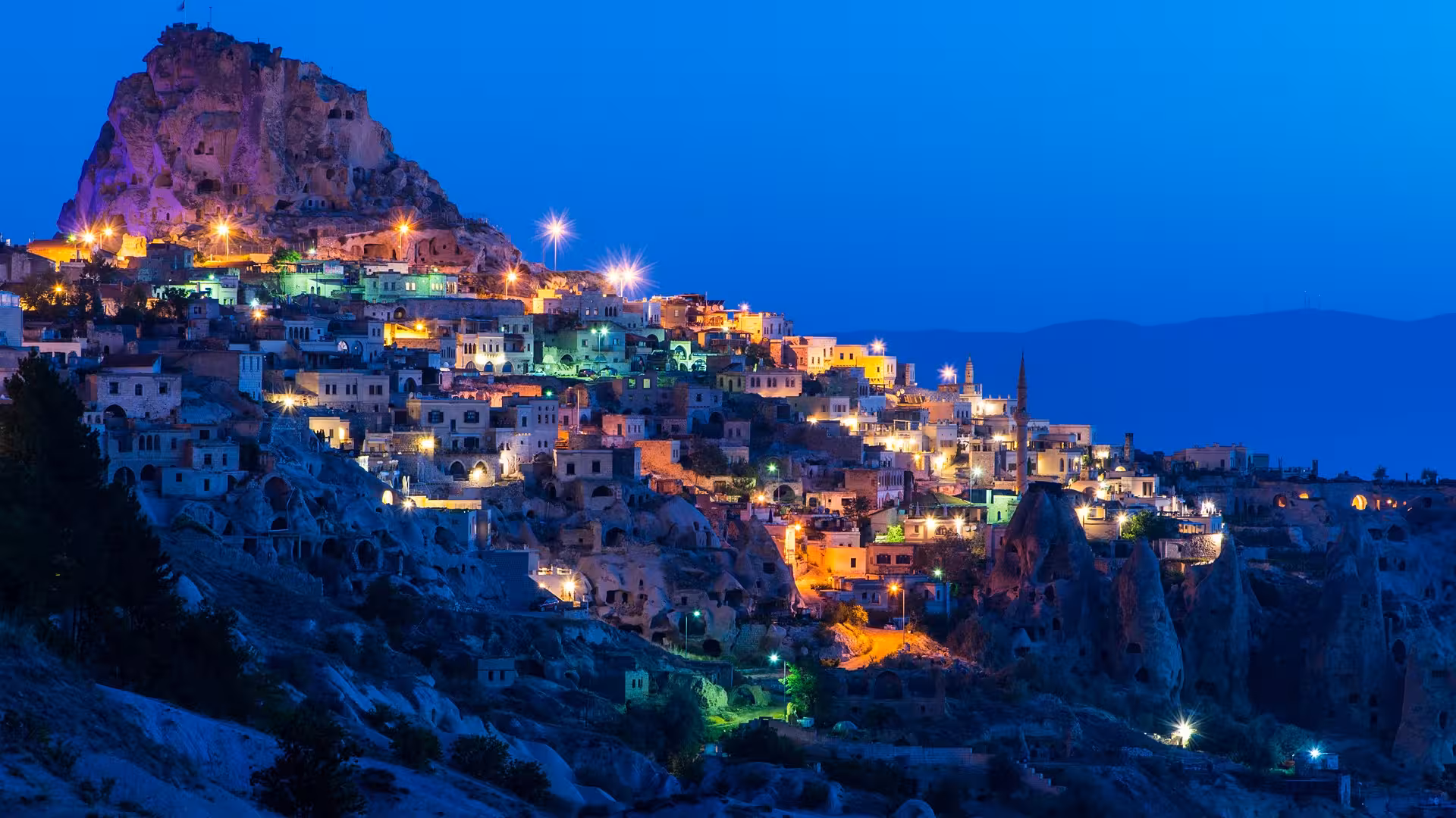 Blue hour view of Uchisar Castle and cave houses in Cappadocia, highlight of 5-day Turkey package