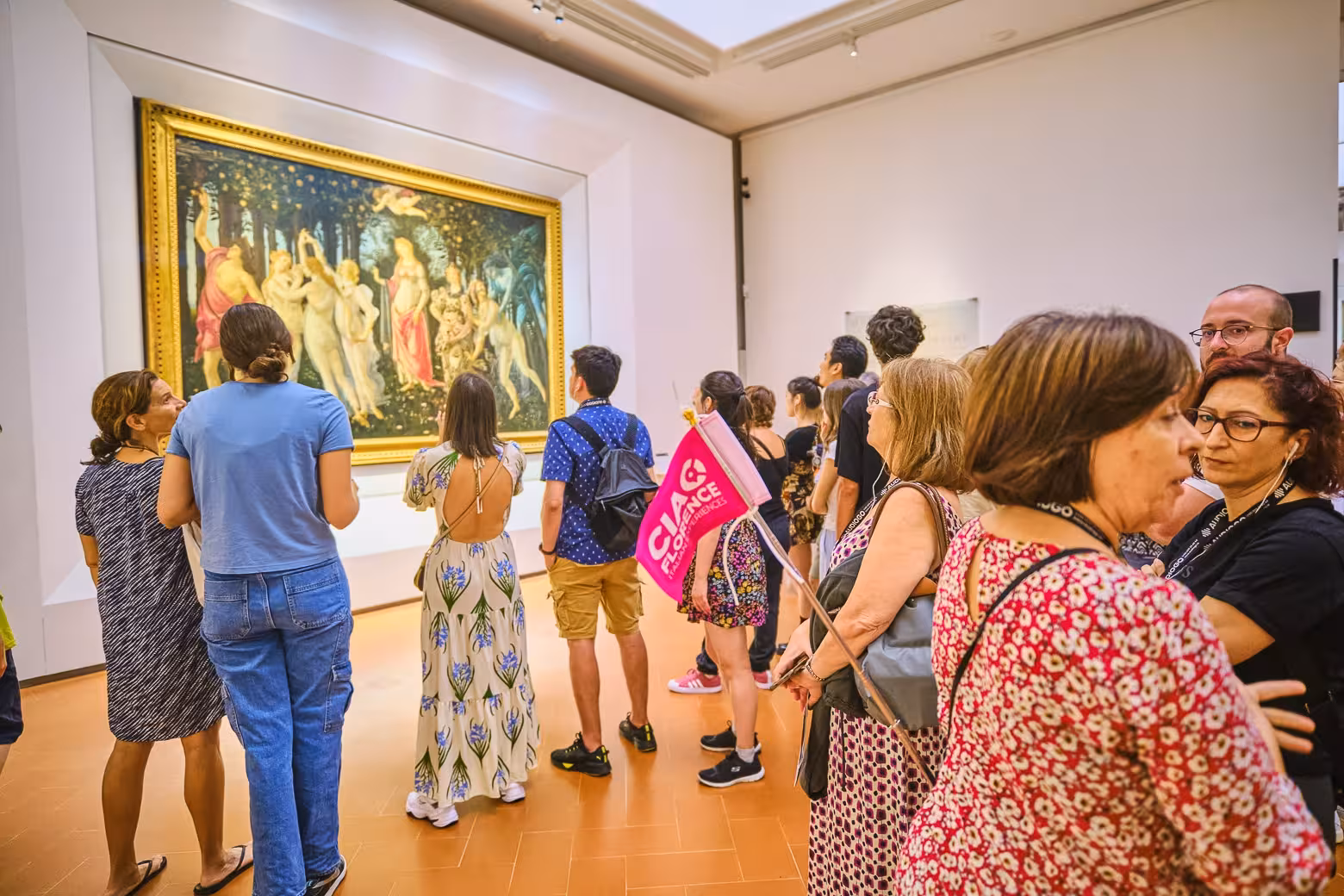 Tour group admiring Botticelli's Primavera during a guided exploration at Uffizi Gallery, Florence.