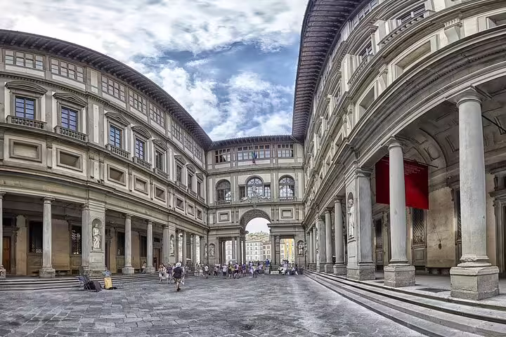 Panoramic view of the Uffizi Gallery courtyard in Florence with Renaissance arches and visitors on a small group tour