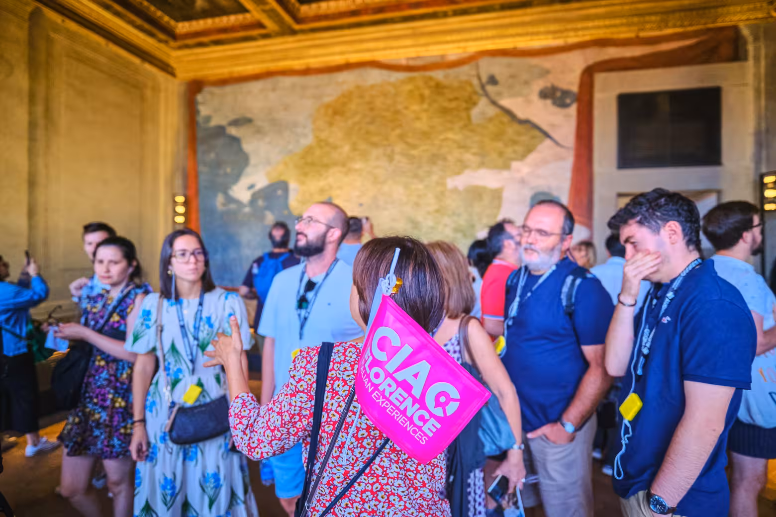 Tour group exploring Uffizi Gallery with guide holding a pink flag, showcasing art and history in Florence.