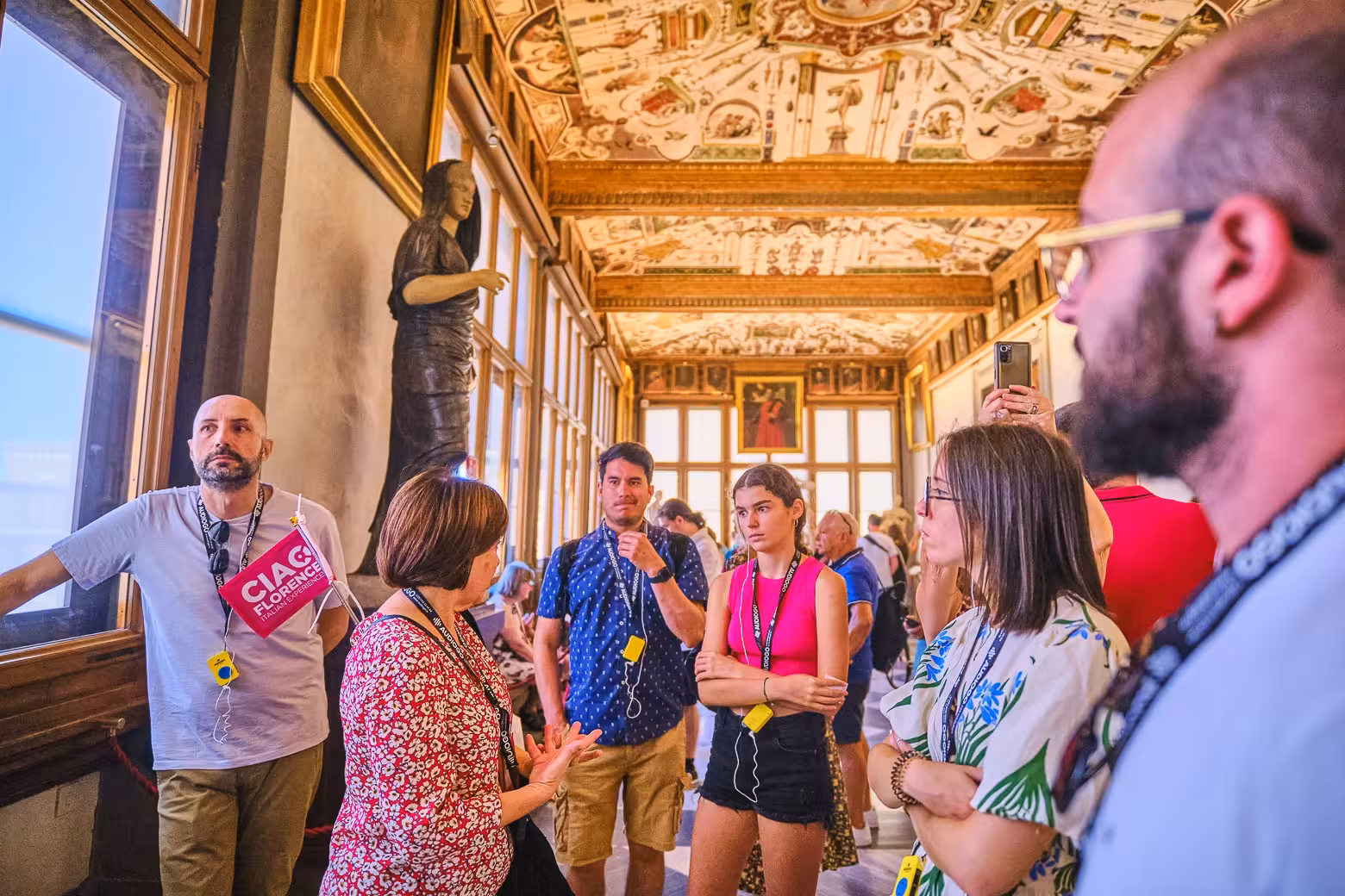 Visitors engage with a guide in a beautifully decorated corridor during the Uffizi Gallery skip-the-line tour in Florence.