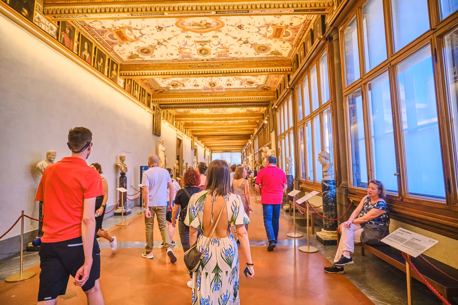 Visitors explore a grand corridor with ornate ceiling and statues on a Uffizi Gallery private tour with skip the line access.