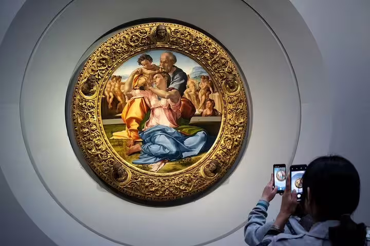 Visitor photographing a famous Renaissance tondo painting during a guided small group tour inside Florence’s Uffizi Gallery