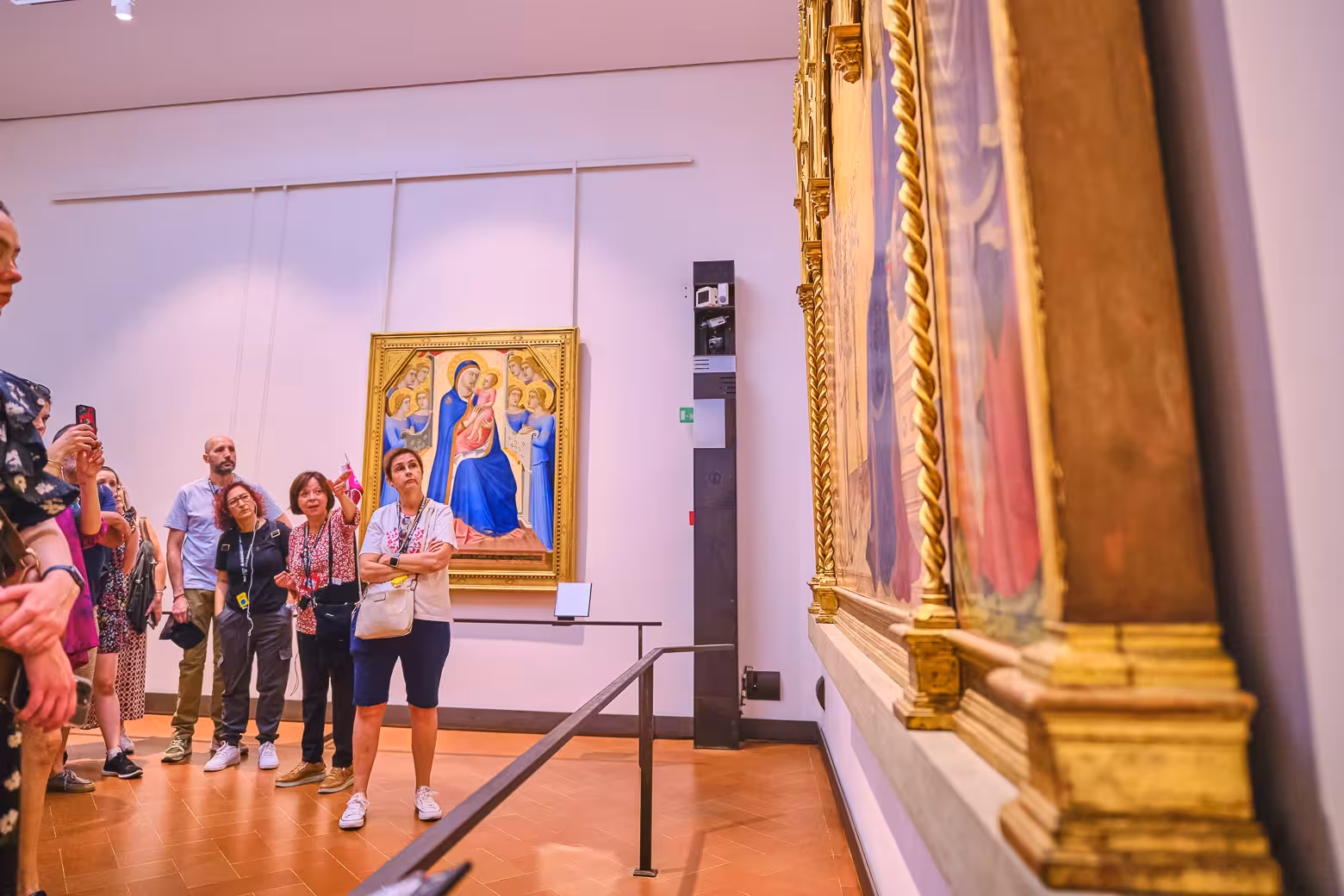 Small group tour observing Renaissance paintings with a guide inside the Uffizi Gallery's art-filled rooms.