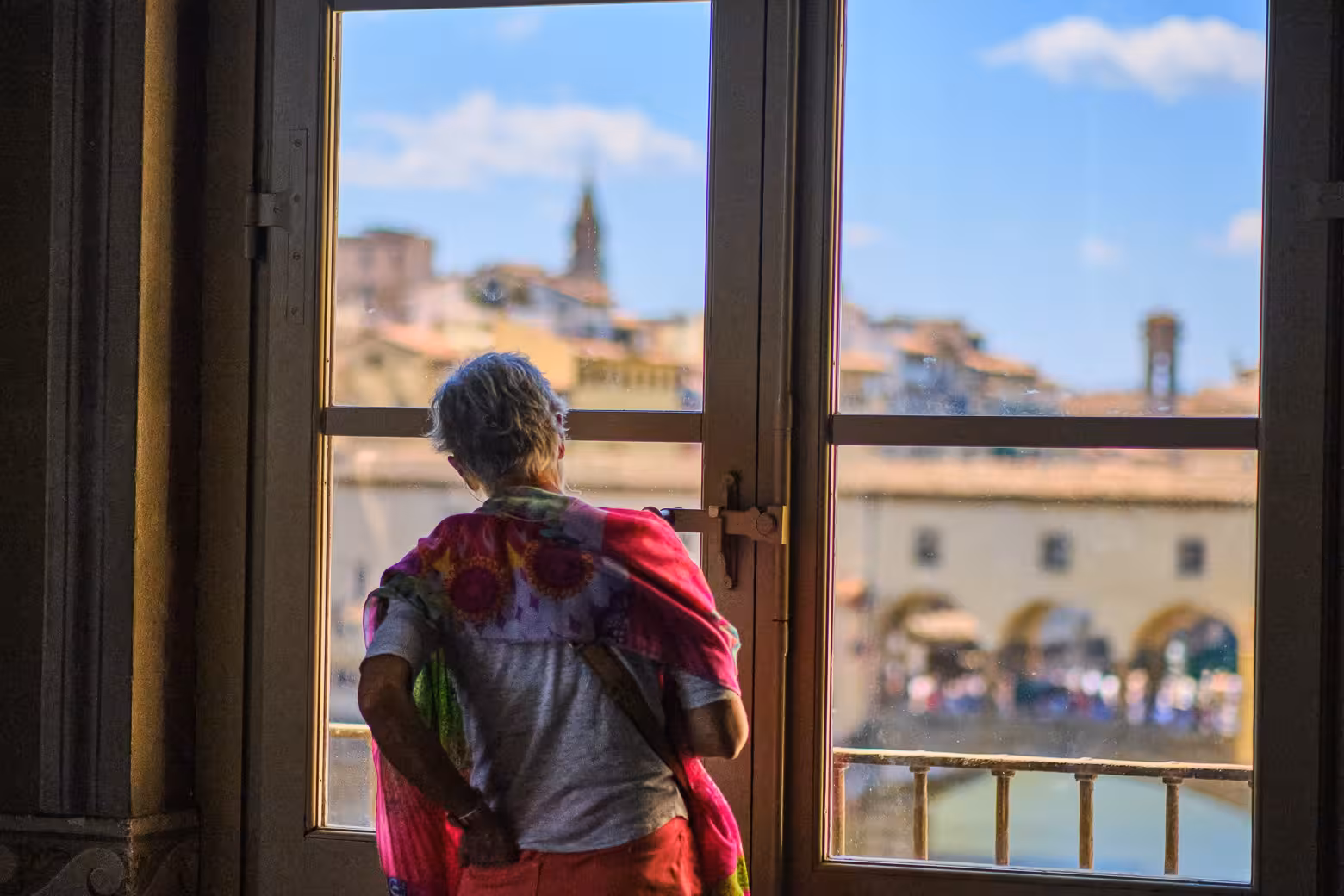 Tourist enjoying scenic views of Florence through a window in the Vasari Corridor.