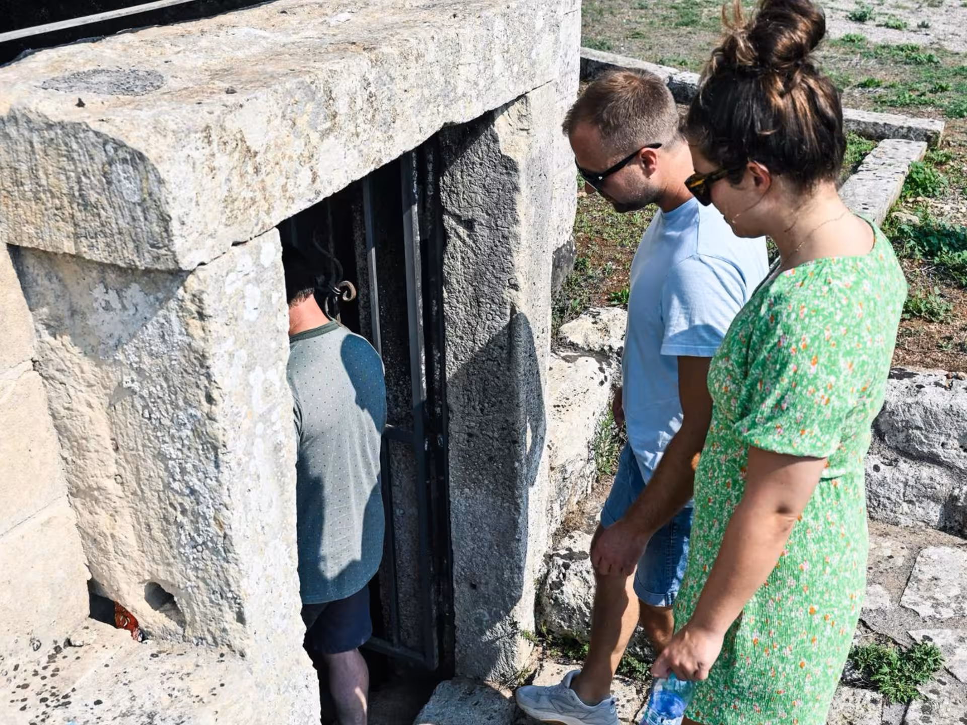Tourists enter an ancient stone entrance leading to the underground olive mill tour near Otranto, Italy.