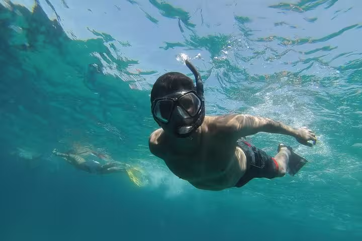 Underwater snorkeler gliding in turquoise sea on Rando-Palmée Getaway around an island, coastal adventure
