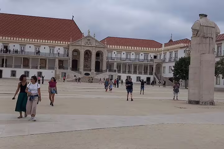 Tourists exploring the historic courtyard of the University of Coimbra during a Tomar-Coimbra day tour.