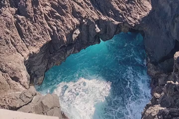 Dramatic coastal rock formation with turquoise waves for Untraveled West Tour's marine exploration.