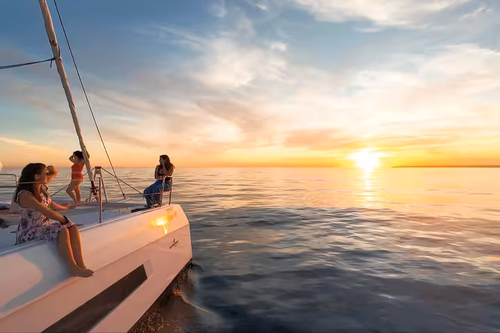 Guests relaxing on a catamaran deck watching a breathtaking golden sunset on a Vilamoura boat cruise