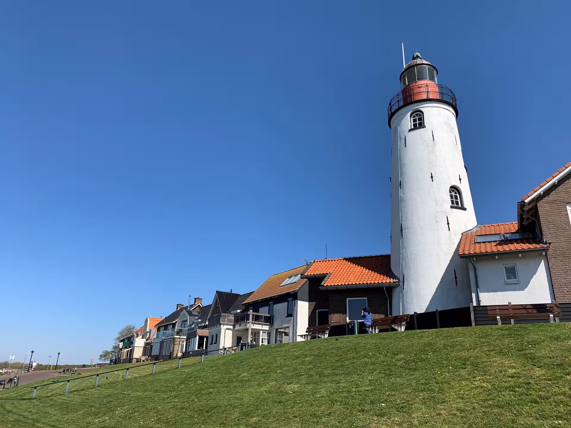 Urk lighthouse and waterfront homes under blue sky, scenic stop on private tour from Amsterdam to Urk village