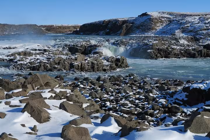 Snow-covered rocky landscape with rushing waterfall at Urridafoss, Iceland in winter