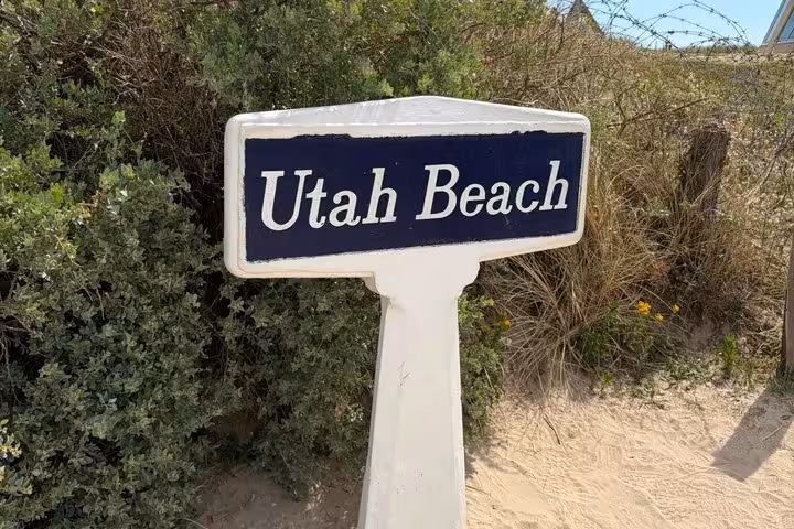 Utah Beach sign on a post surrounded by sand dunes and green shrubs in Normandy, France