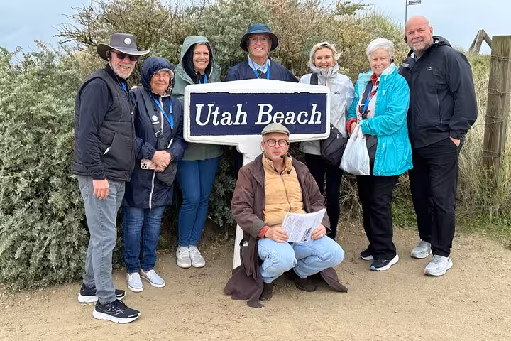 Group of tourists posing at Utah Beach sign during D-Day Normandy tour