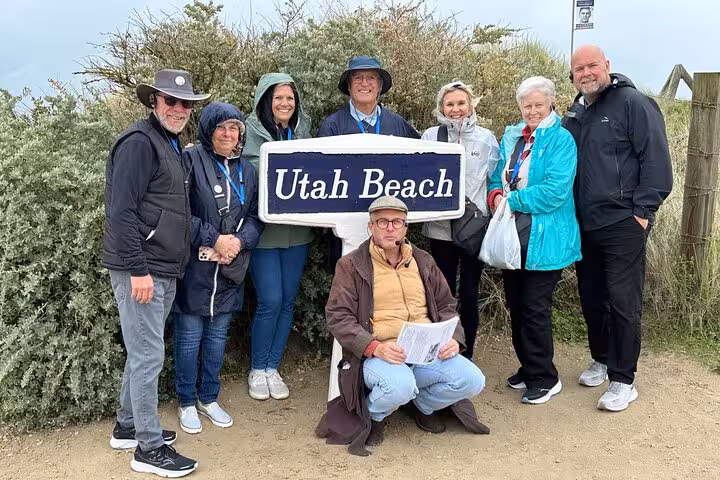 Tour group posing at Utah Beach sign on D-Day Beaches guided tour from Le Havre