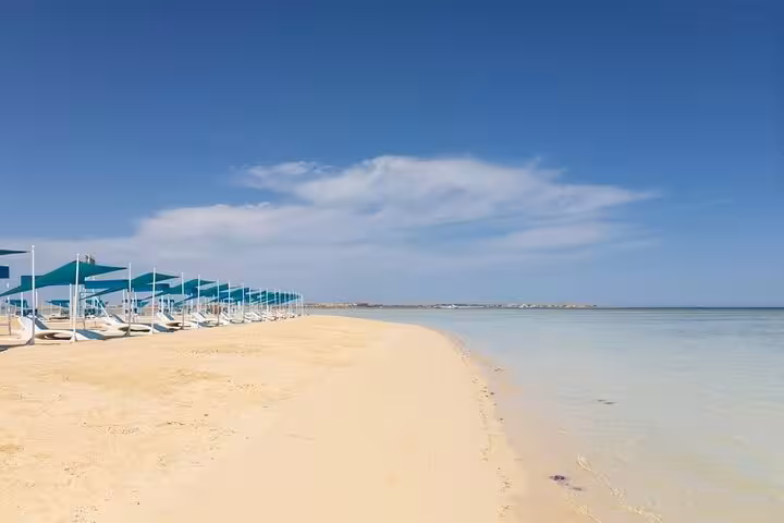 Wide shoreline at Utopia Bianca Island with calm Red Sea lagoon and sunbeds, Hurghada snorkel day tour