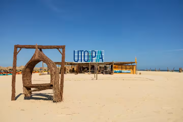Utopia Island beach club with wicker swing seat on white sand beach, Hurghada