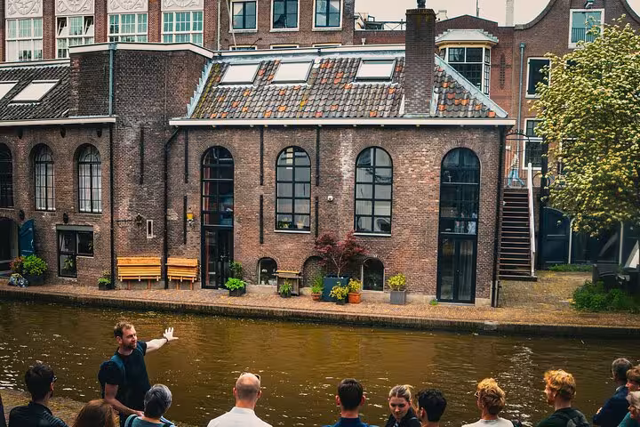 Local guide explaining Utrecht canal-side history to small group tour, ideal for private group tour with lunch