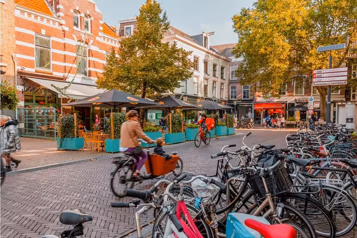 Busy Utrecht city square with cyclists and parked bikes near outdoor café terraces and historic brick buildings