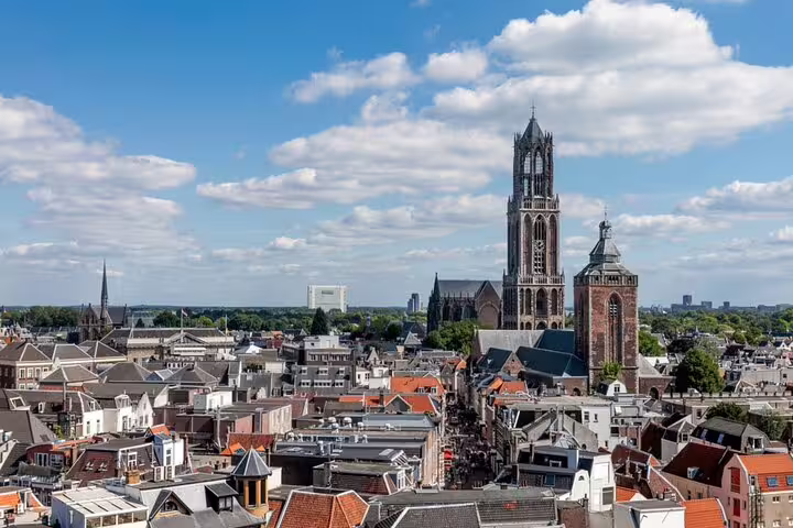Aerial view of Utrecht city center with iconic Dom Tower and historic rooftops under blue sky