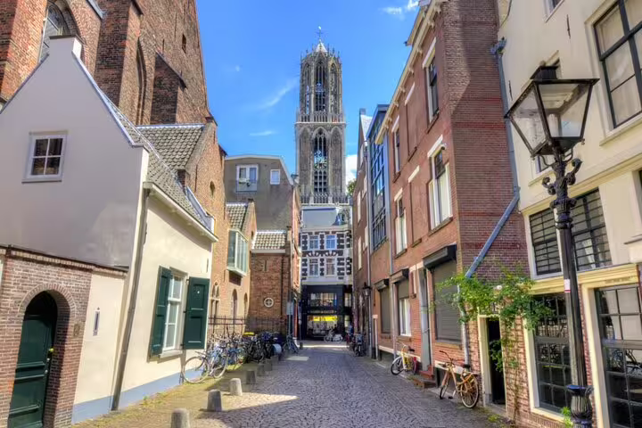 Cobblestone street in Utrecht old town with Dom Tower rising above historic brick buildings