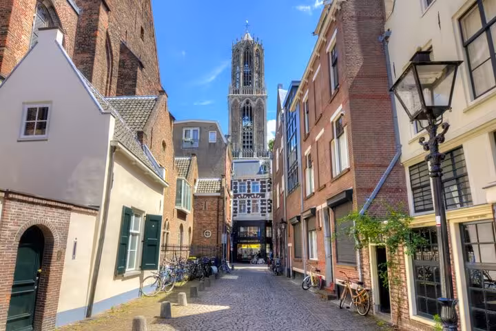 Cobblestone street in Utrecht's medieval old town with Dom Tower rising above historic brick buildings