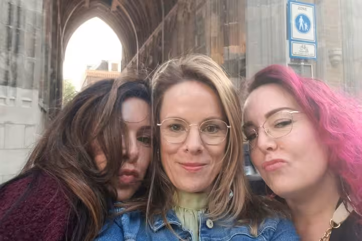 Three women taking a selfie in front of a medieval Gothic arch in Utrecht city center