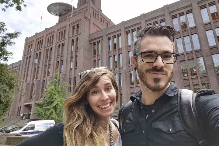 Couple smiling in selfie in front of historic red brick building in Utrecht