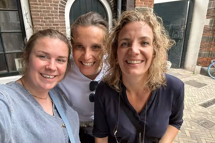 Three smiling women posing for a selfie on a historic brick street in Utrecht