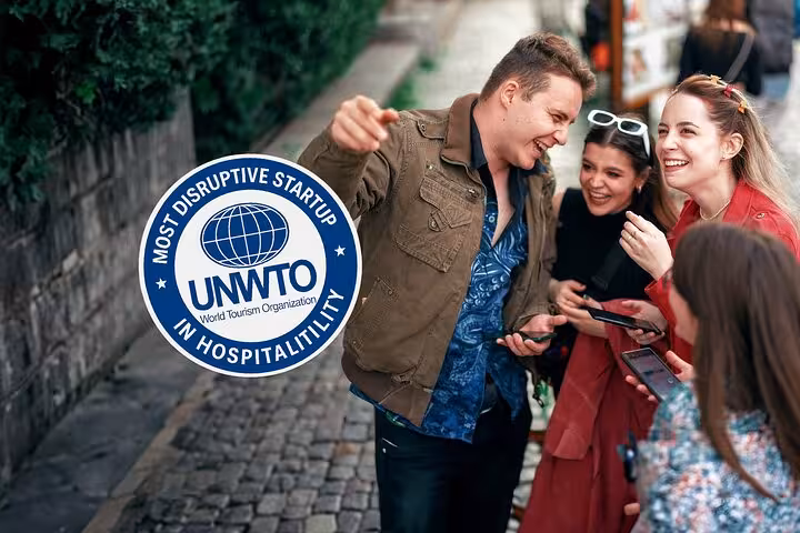 Tour guide pointing directions to smiling tourists on a cobblestone street, UNWTO Most Disruptive Startup award badge