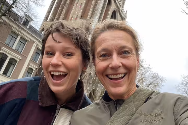 Two smiling women taking a selfie in front of a medieval church tower in Utrecht