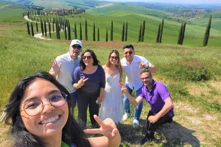Group of tourists enjoying the scenic views of Val D'Orcia's rolling hills and cypress trees during their tour.