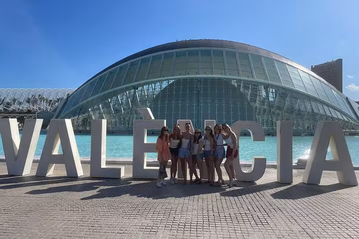 Tour guests pose by giant VALENCIA letters at City of Arts and Sciences on a guided bike tour from Ruzafa