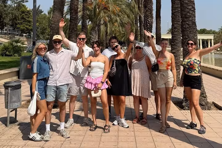 Happy bike tour group in Valencia’s Turia Gardens, waving on a Dutch guided cycling tour in summer