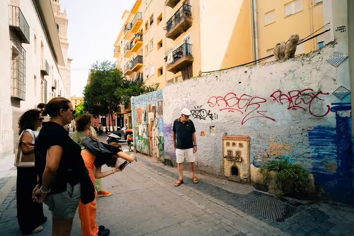 A group explores Valencia's vibrant street art on a private family tour, capturing cultural insights and local charm in a sunny alley.