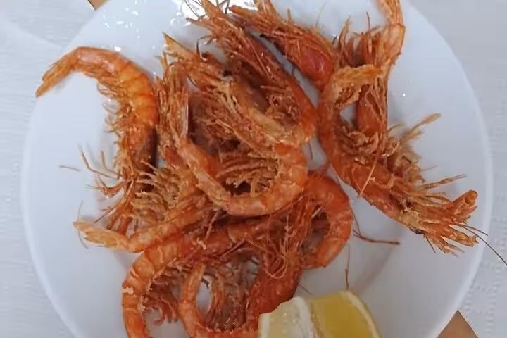 Plate of fried prawns with lemon, a classic seafood tapa on the Valencia gourmet tapas tour by bike or on foot
