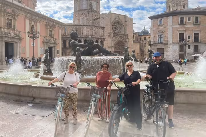 Guided Valencia bike tour group at Plaza de la Virgen fountain near Cathedral, Ruzafa city highlights